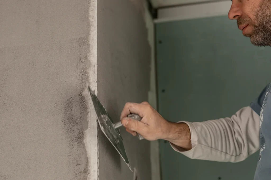 Une personne qui répare une fissure mur intérieur horizontal vertical traversante