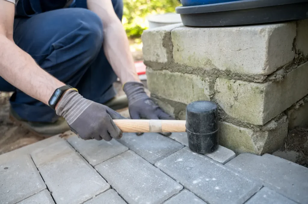 Une personne qui répare un pavé autobloquant descellé qui bouge